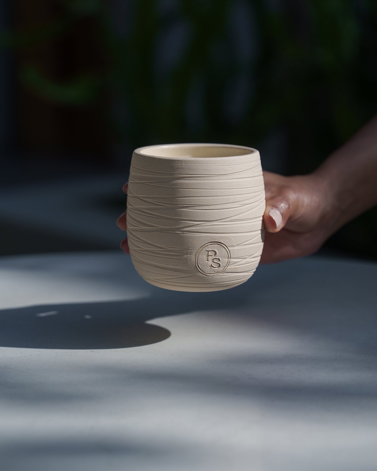 A hand setting the candle down on a sunlit marble table