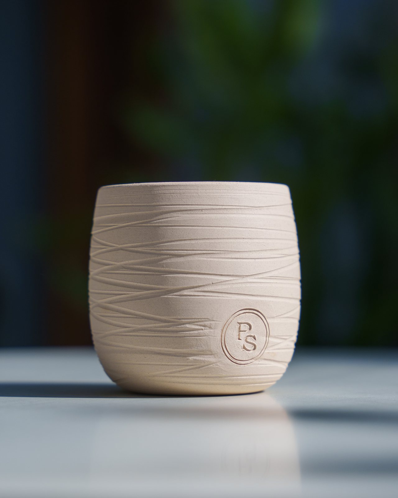 The hand-thrown stoneware candle vessel on a marble table